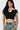 SaltTree model wearing a black cropped polo top with a white contrast collar and short sleeves in seamless fabric.