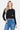 SaltTree model wearing a black slim-fit cropped button-up cardigan with long sleeves and high-waisted blue jeans.