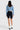 SaltTree model wearing an Enjean stone wash cropped denim jacket with black biker shorts and white boots, back view.