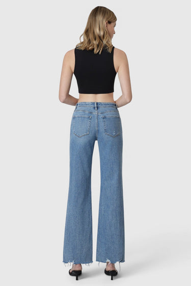 SaltTree model wearing Flying Monkey high rise vintage flare jeans in medium wash with a raw hem, back view.