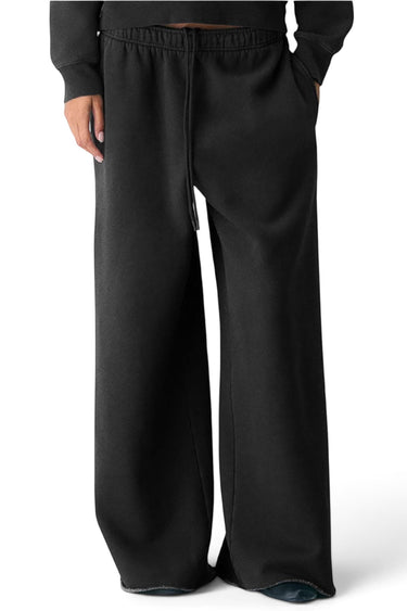 SaltTree Reflex black fleece sweatpants with an oversized relaxed leg, mid-rise drawstring waist, and raw hem detail.