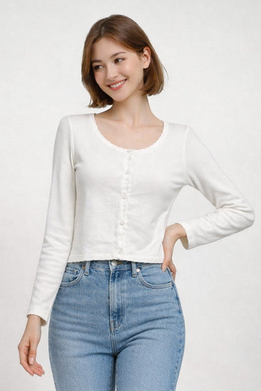 SaltTree model wearing a white long sleeve cropped cardigan with a scalloped edge and ribbed knit texture.
