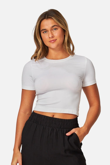 Model wearing a white SaltTree Love Poem seamless crew-neck crop top with cap sleeves against a plain background