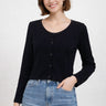 SaltTree model wearing a black ribbed knit cropped cardigan with long sleeves and a scalloped edge over blue jeans.