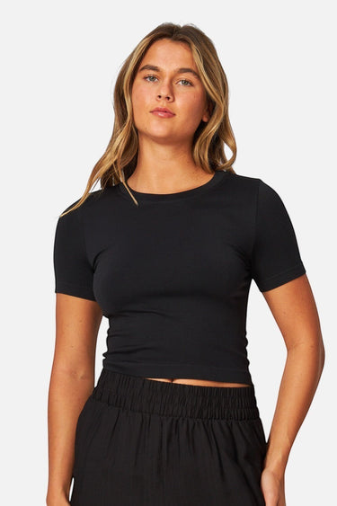 SaltTree model wearing a black Love Poem seamless crew-neck crop top with cap sleeves and slim-fit stretch fabric.