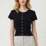 SaltTree model wearing a black short sleeve button-front knit cardigan with a round neckline and fitted waist.