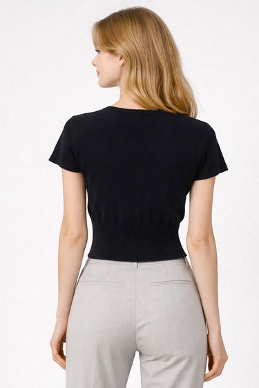 Model wearing a black SaltTree short sleeve knit cardigan with a round neckline and fitted waist, back view.