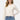 SaltTree model wearing a cream Dreamers slim-fit cropped button-up cardigan with long sleeves and blue denim jeans.