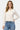 SaltTree model wearing a cream Dreamers slim-fit cropped button-up cardigan with long sleeves and blue denim jeans.