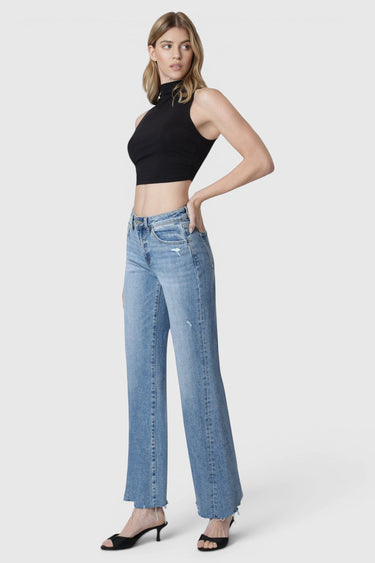 Model wearing SaltTree Flying Monkey high rise vintage flare jeans in medium wash with raw hem and slant side seam.