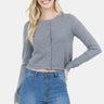 SaltTree model wearing a grey slim-fit cropped button-up cardigan by Dreamers with long sleeves and blue jeans.