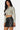 SaltTree Love Poem black faux leather A-line mini skort with front slit worn by a model in a beige cropped top