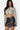 SaltTree Love Poem black faux leather mini skort with front slit worn by a model with a beige zip-up crop top