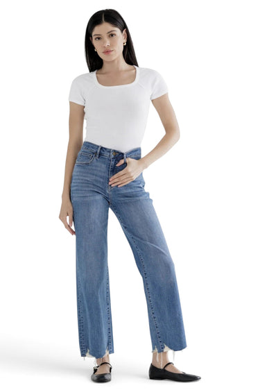 SaltTree model wearing Mica Denim high rise wide leg jeans in medium blue with a distressed raw hem and white top.