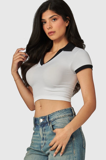 SaltTree model wearing a white cropped polo top with a black contrast collar and short sleeves in seamless fabric.