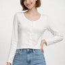 SaltTree model wearing a white long sleeve cropped cardigan with a scalloped edge and ribbed knit texture.